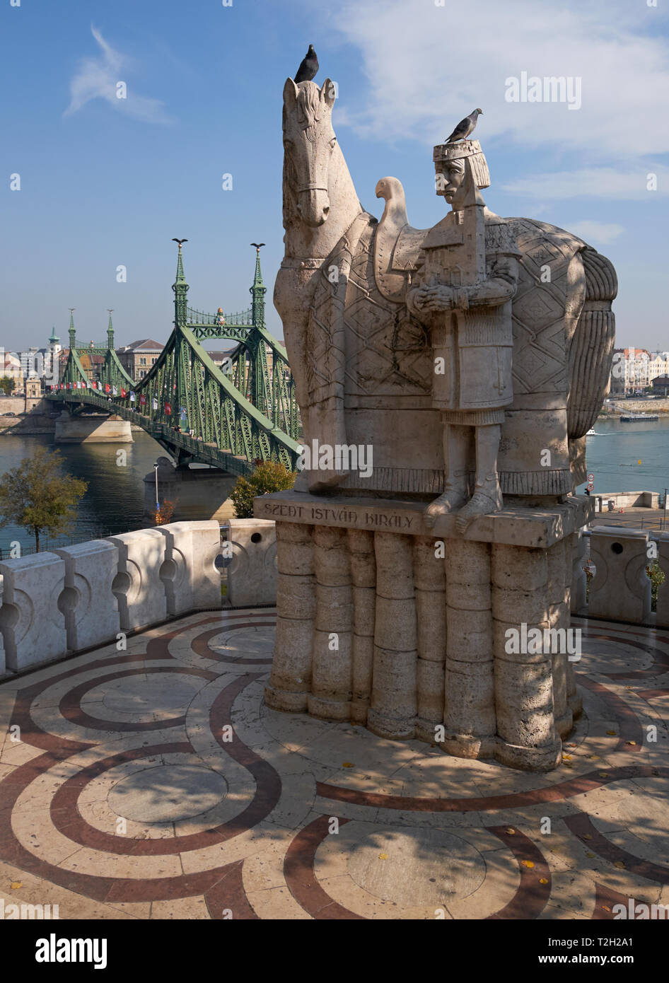 Statue des hl. Stephanus außerhalb der Höhle Kirche, Gellertberg, Budapest, Ungarn, mit der Brücke im Hintergrund. Stockfoto