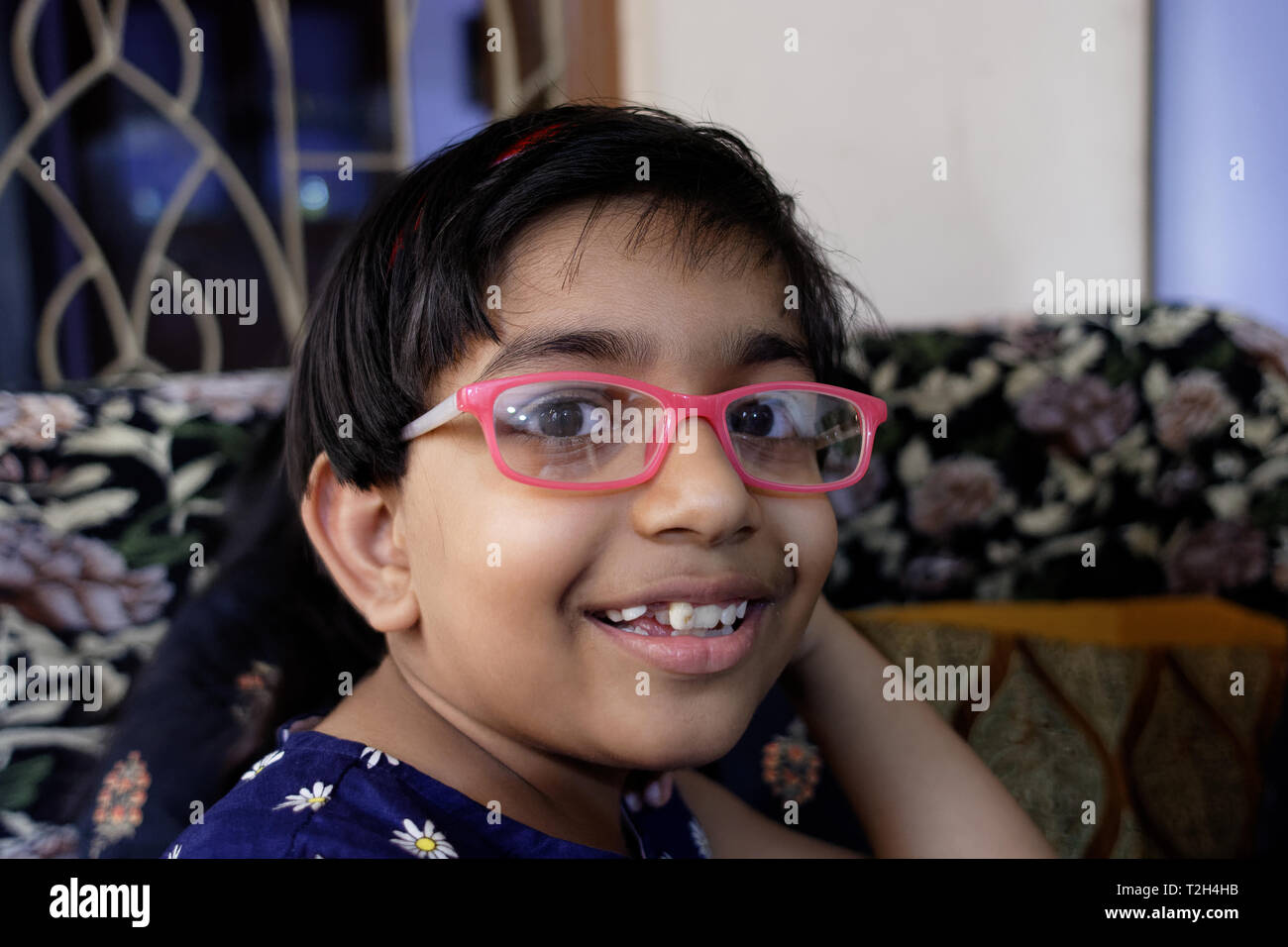 Kleine indische Mädchen mit rosa Brille auf spielerische Stimmung zu Hause lächeln Stockfoto