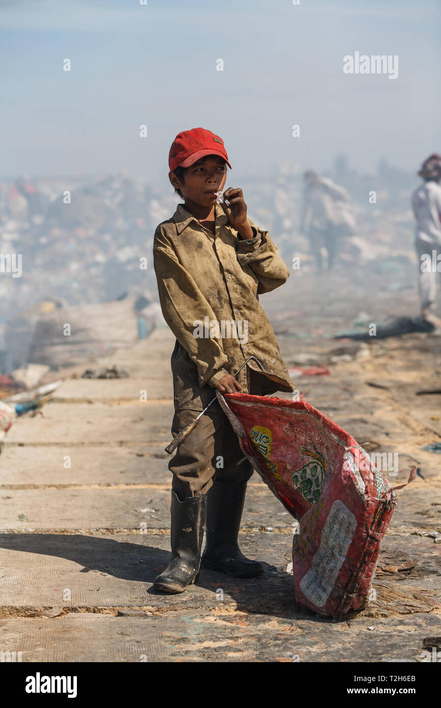 Portrait einer jungen kambodschanischen Junge in einer roten Baseball Hut Tragetasche zu, in der ein Lächeln auf Platz gefunden Schätze aus der Müllhalde Stockfoto