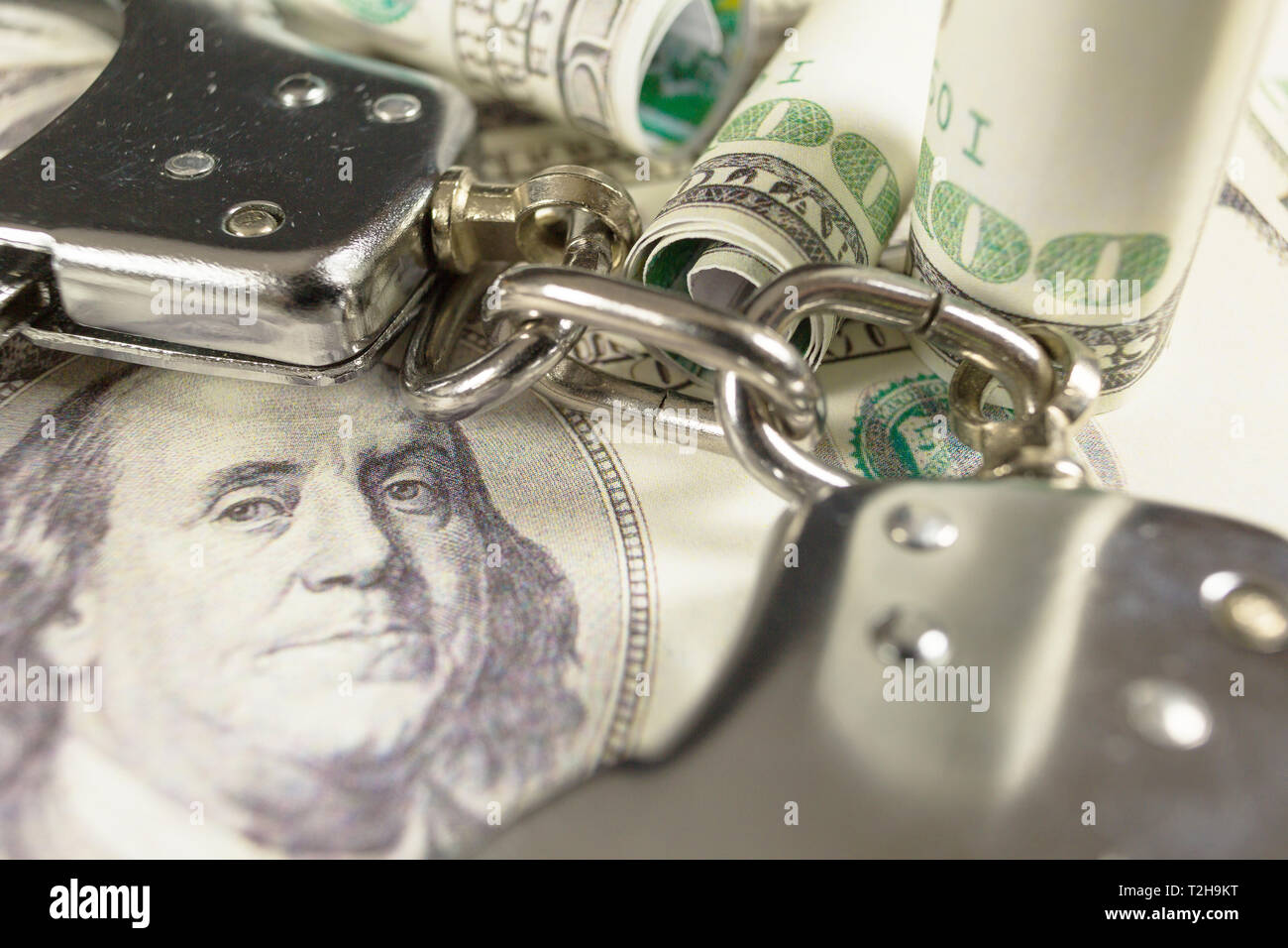 Handschellen mit Hundert-Euro-Scheine als Hintergrund. Kriminalität oder Verhaftung Konzept. Stockfoto