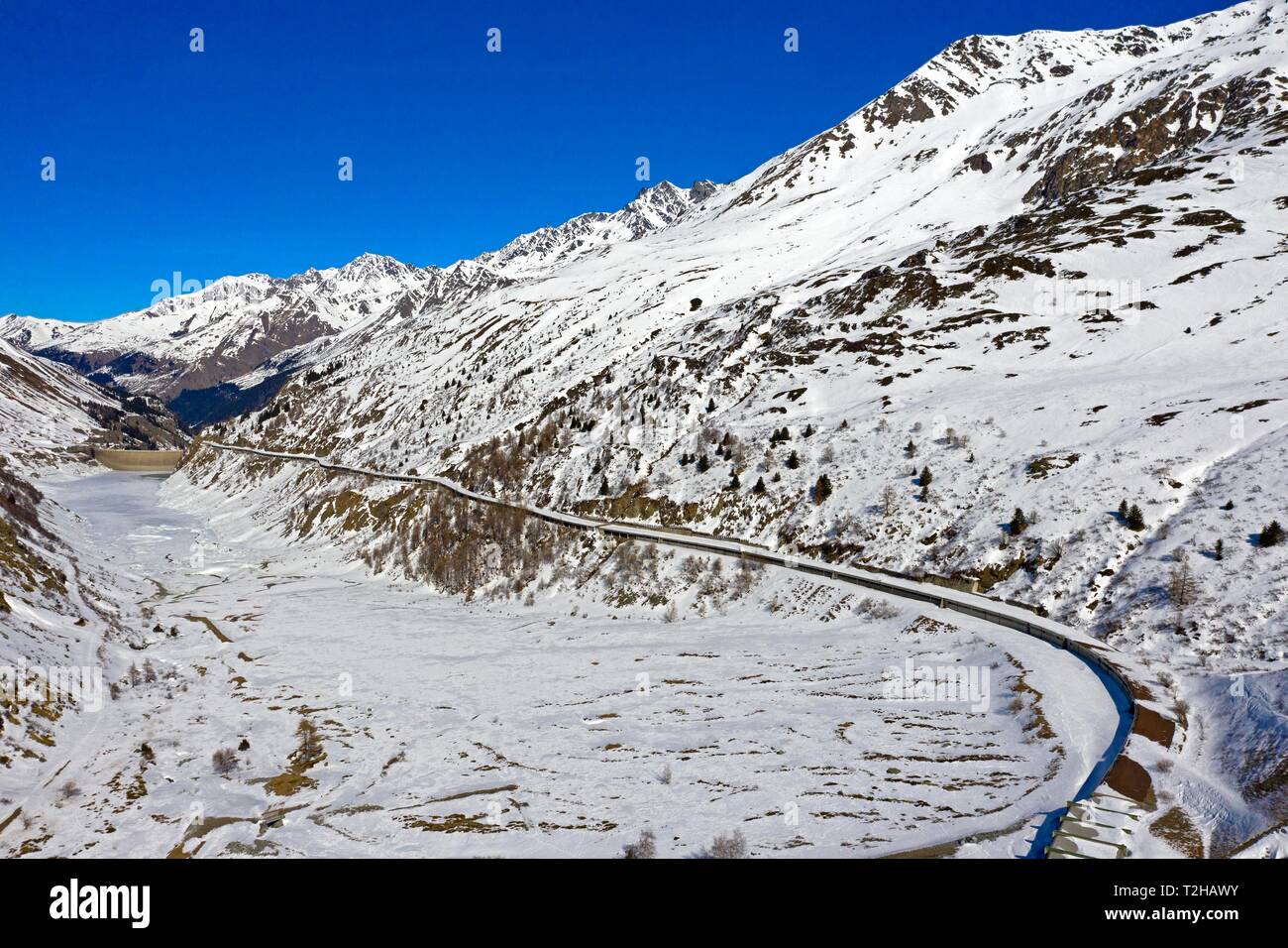 Überdachte Country Road auf dem Schnee - Lac des Toules Behälter vor dem Großen St. Bernhard Tunnel, Luftaufnahme, Bourg-St-Pierre, Entremont abgedeckt Stockfoto