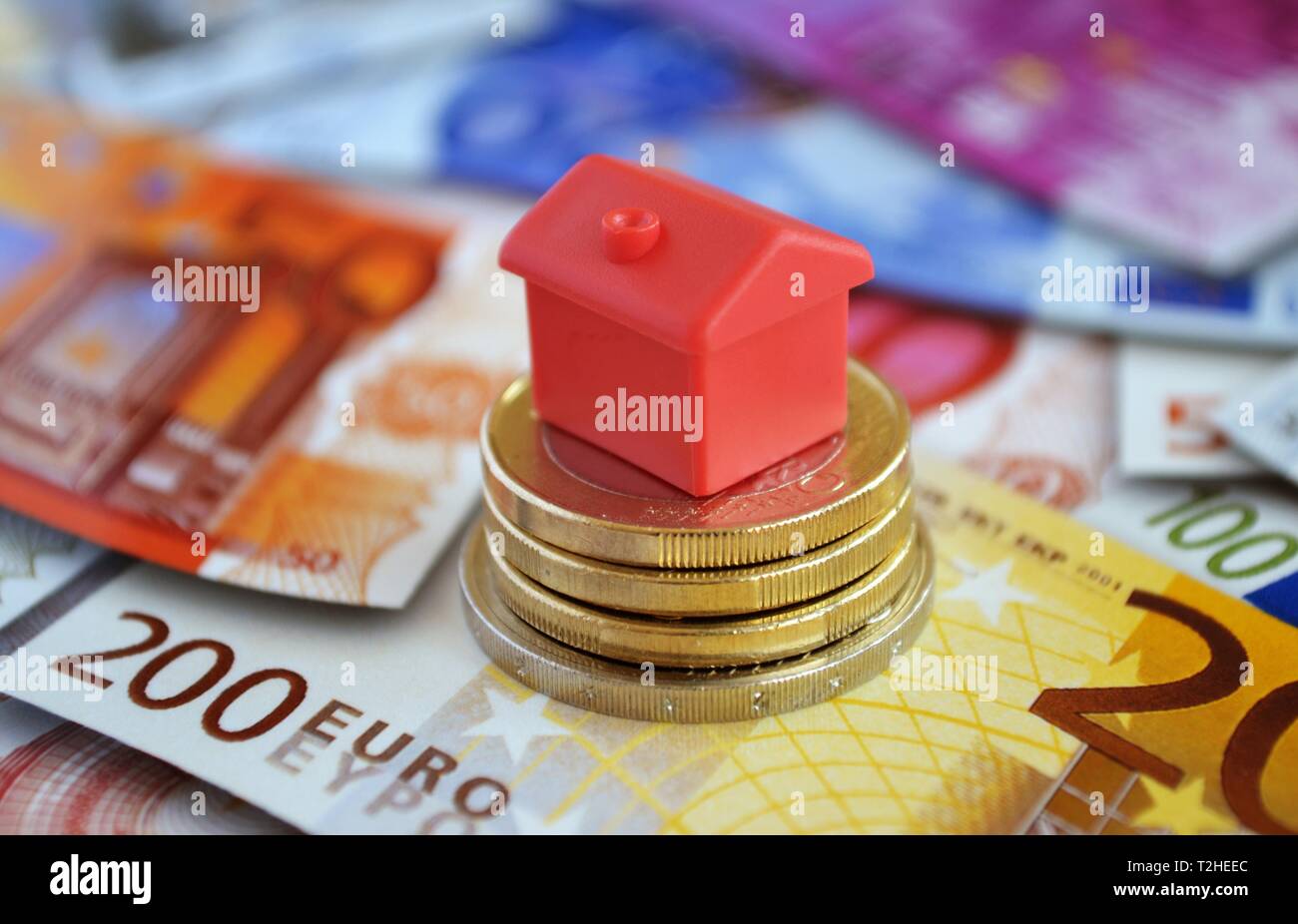 Ferienhaus auf den Haufen Geld Münzen und Banknoten, Symbol Foto Immobilien Finanzierung, Deutschland Stockfoto