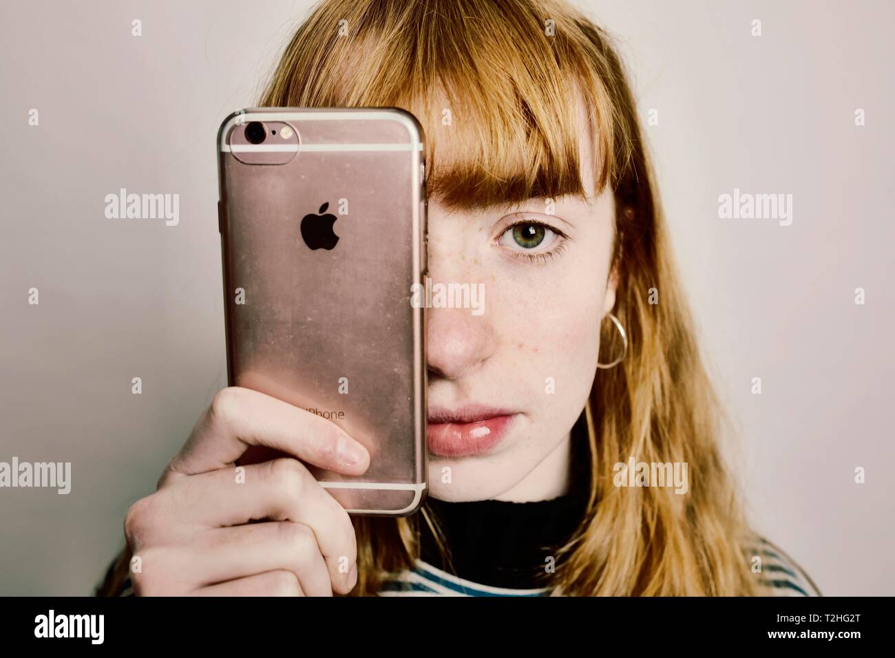 Mädchen mit einem Apple iPhone, Apple Logo als Auge, studio Shot, Deutschland Stockfoto