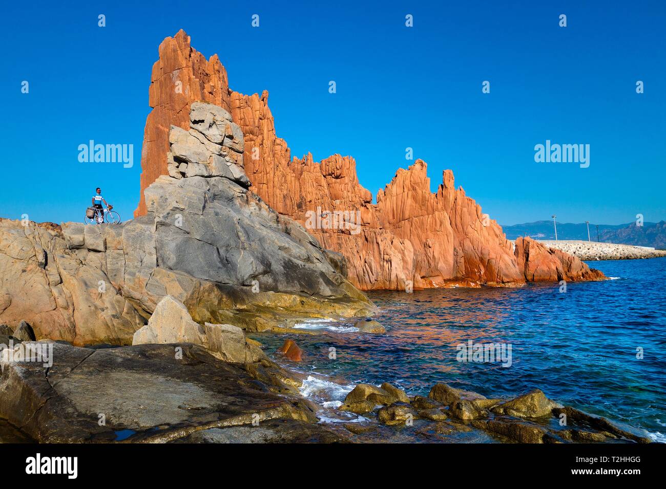 Mann mit Fahrrad auf den Felsen, vom Meer in Arbatax, Sardinien, Italien, Europa Stockfoto