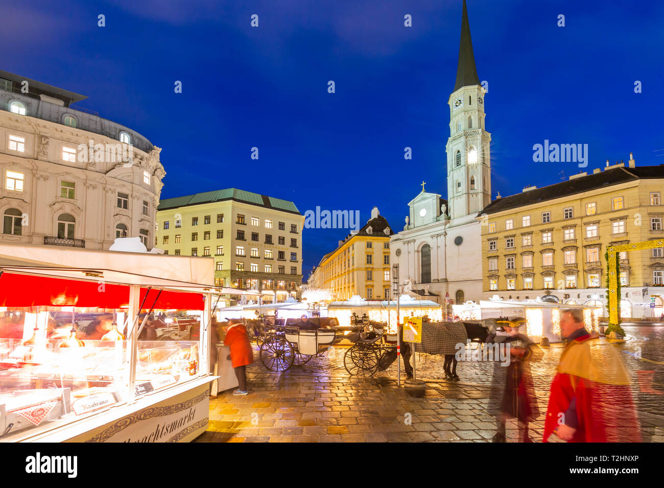 Blick auf Weihnachtsmärkten Stände und St. Michael Katholische Kirche in Michaelerplatz in der Dämmerung, Wien, Österreich, Europa Stockfoto