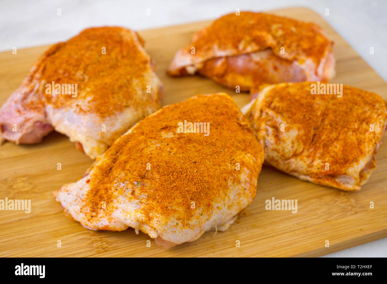 Rohe Hühnerkeule gewürzt mit Gelbwurz und Paprika Stockfoto