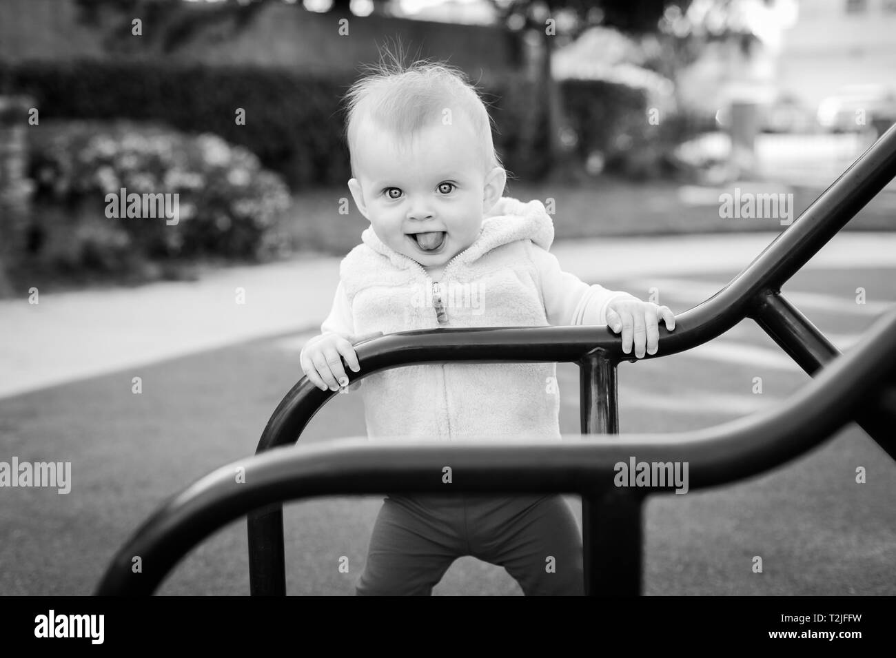 Schwarz-weiß Foto eines acht (8) Monate alten Baby Mädchen stehen und Spaß im Park in Playa Del Rey, CA. Stockfoto