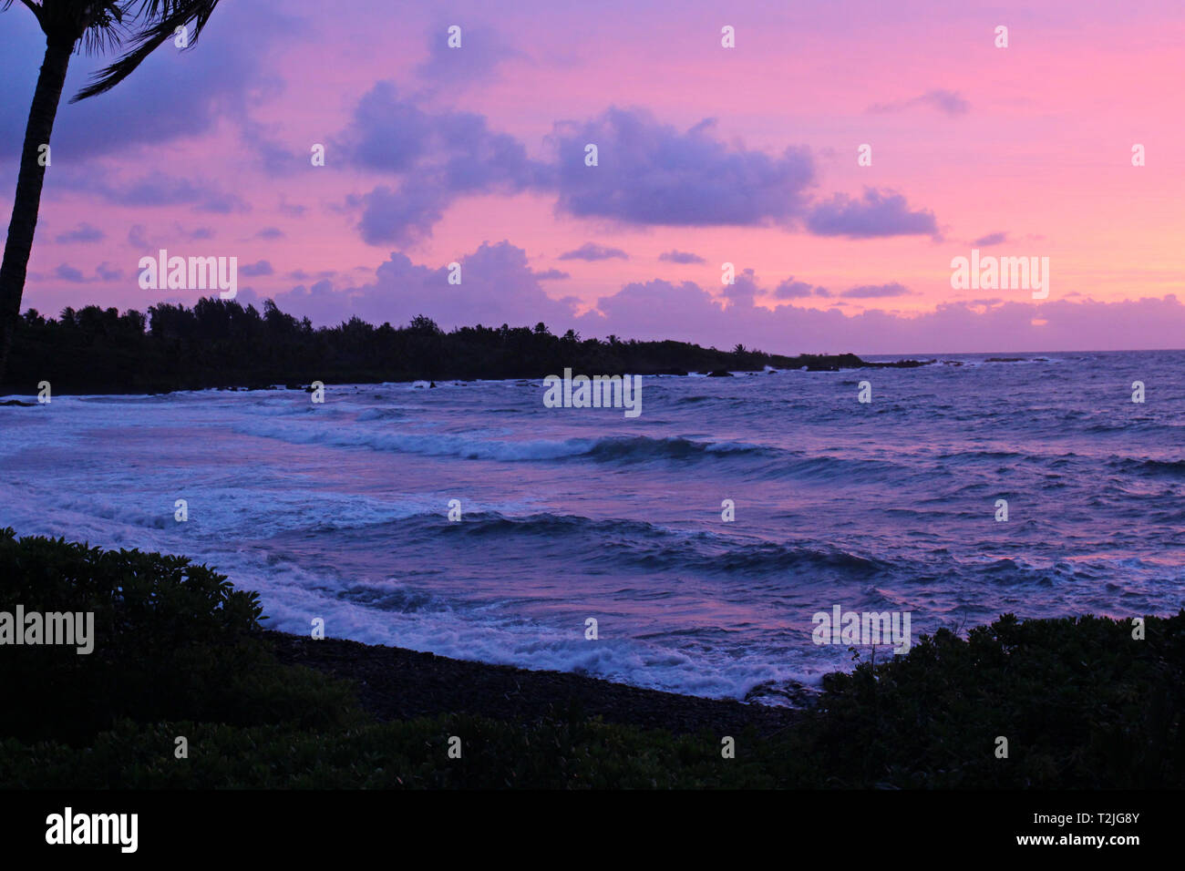 Einen traumhaften Sonnenuntergang in Violett, Rosa- und Blautönen aus dem Pazifischen Ozean von Hana Bay in Hana, Maui, Hawaii, USA widerspiegelt Stockfoto