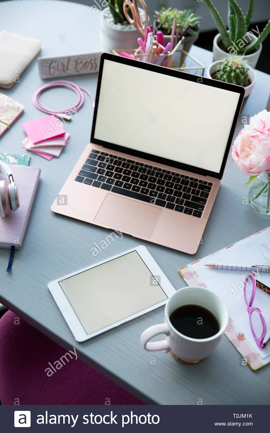Pinkfarbener Laptop, Kaffee und Bürobedarf auf Schreibtisch Stockfoto