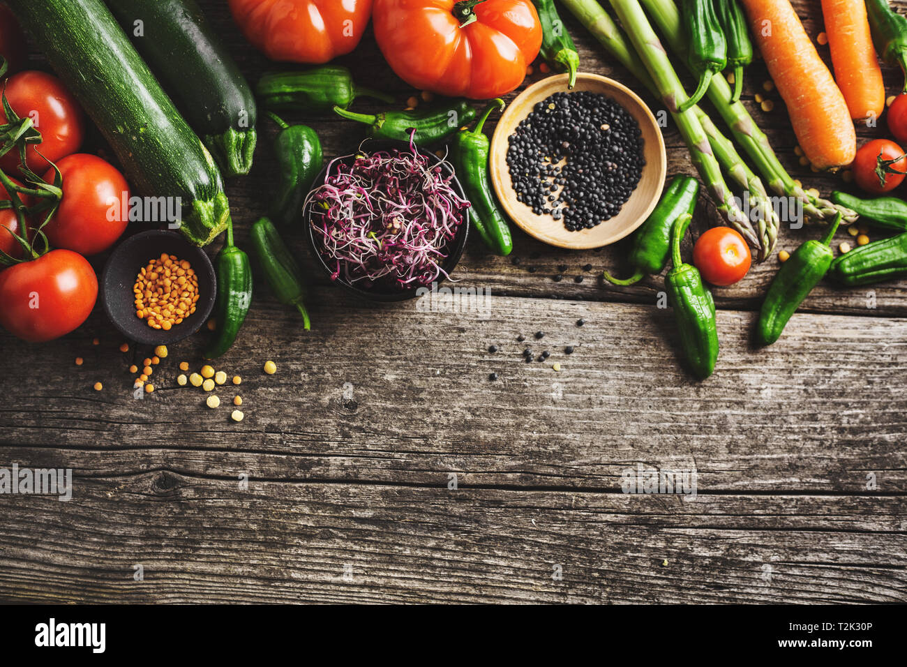 Gesundes essen Hintergrund. Sauber Essen, vegan, vegetarisch essen Konzept. Verschiedene organische Gemüse auf Holz- Hintergrund. Ansicht von oben mit Platz kopieren. Stockfoto