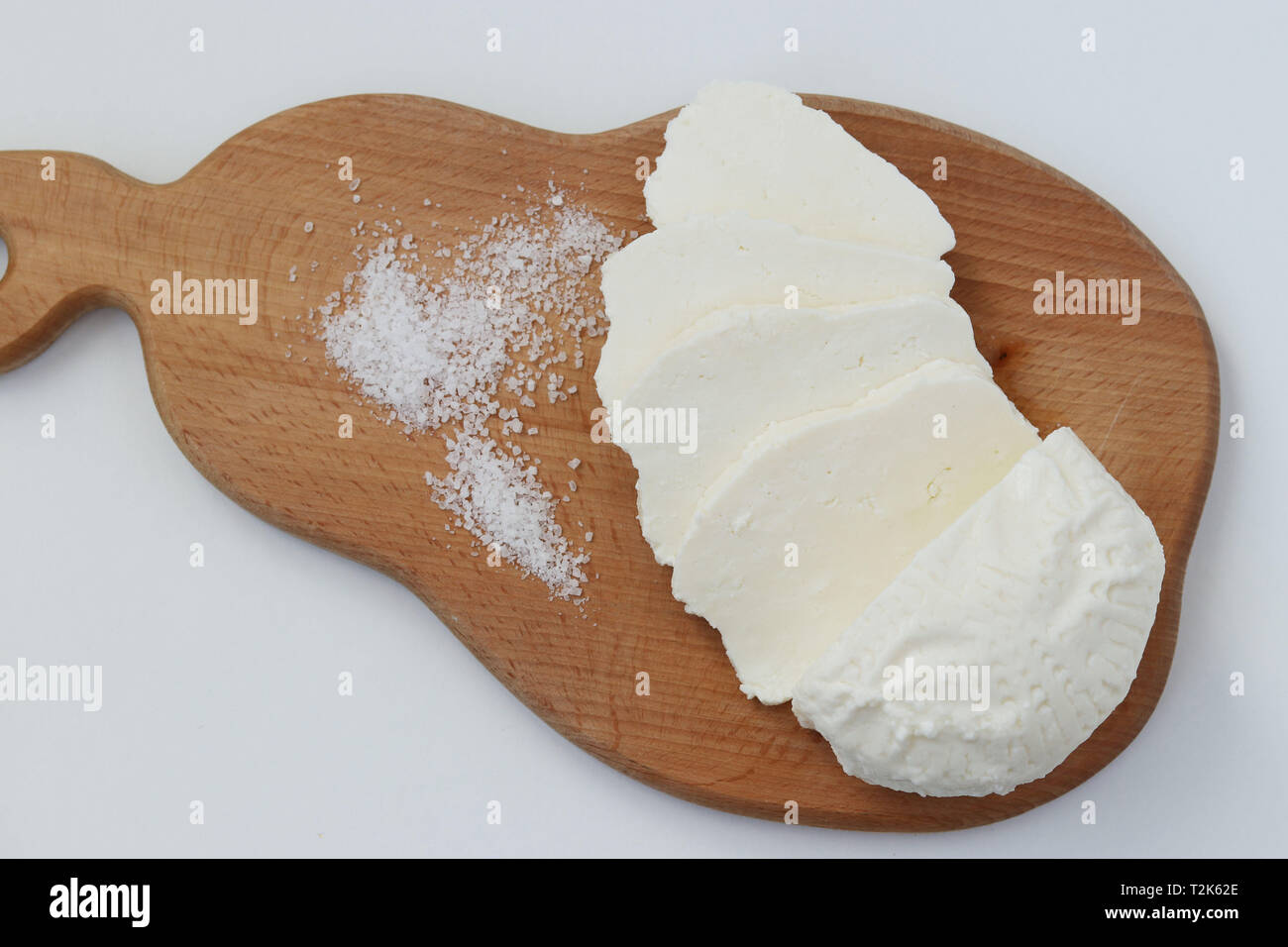 Hausgemachte geschnitten Adyghe Käse auf Holzbrett liegt auf einem weißen Hintergrund, Ansicht von oben Stockfoto