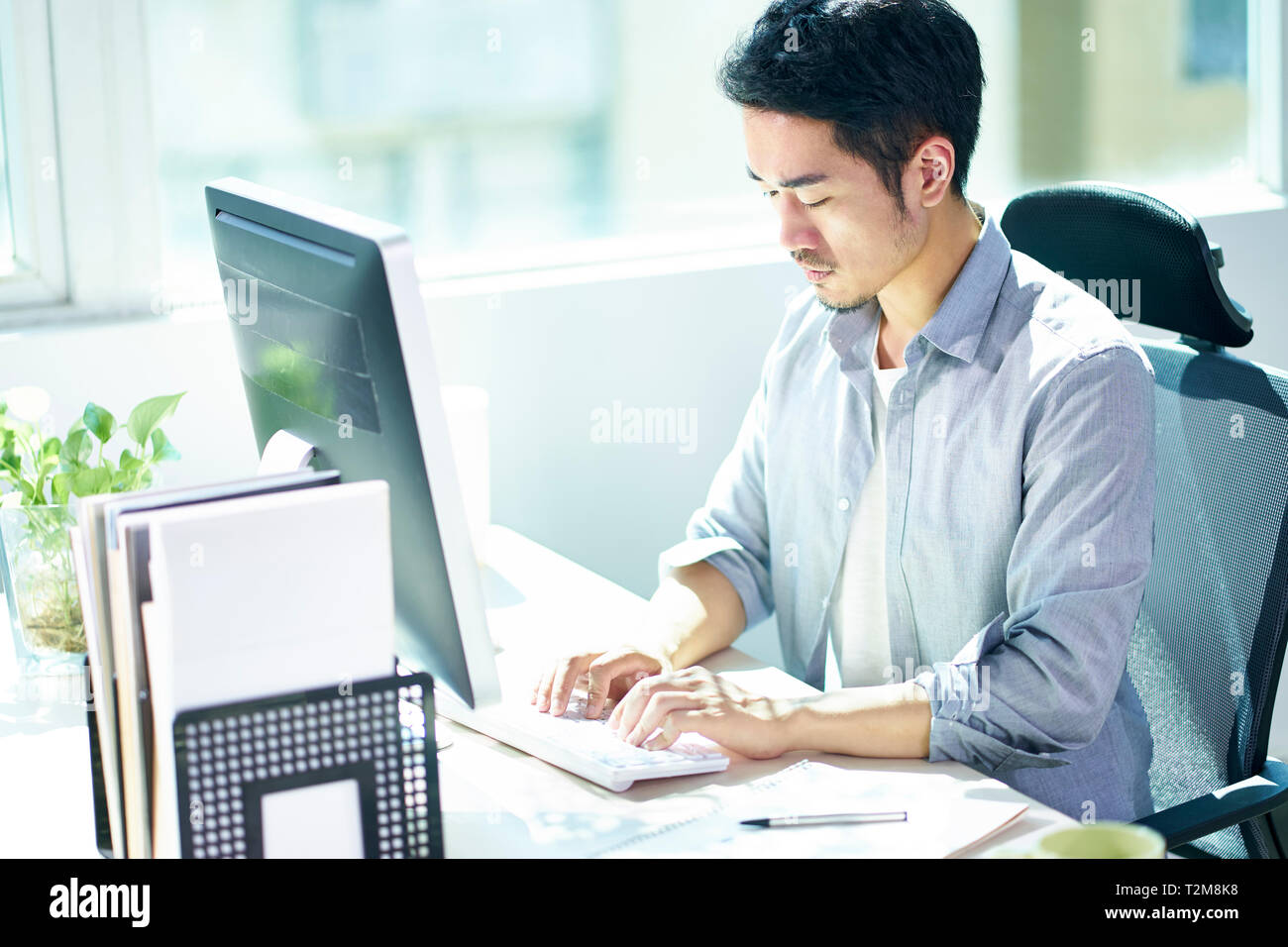 Hohe Betrachtungswinkel und einer jungen asiatischen Geschäftsmann Unternehmer mit Desktop-PC im Büro. Stockfoto