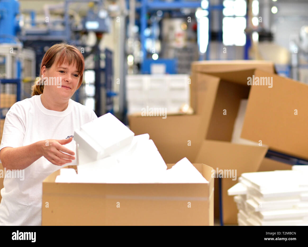 Frau arbeitet in der Versandabteilung eines Unternehmens und Packs Styropor Komponenten in Pakete für den Kunden. Stockfoto