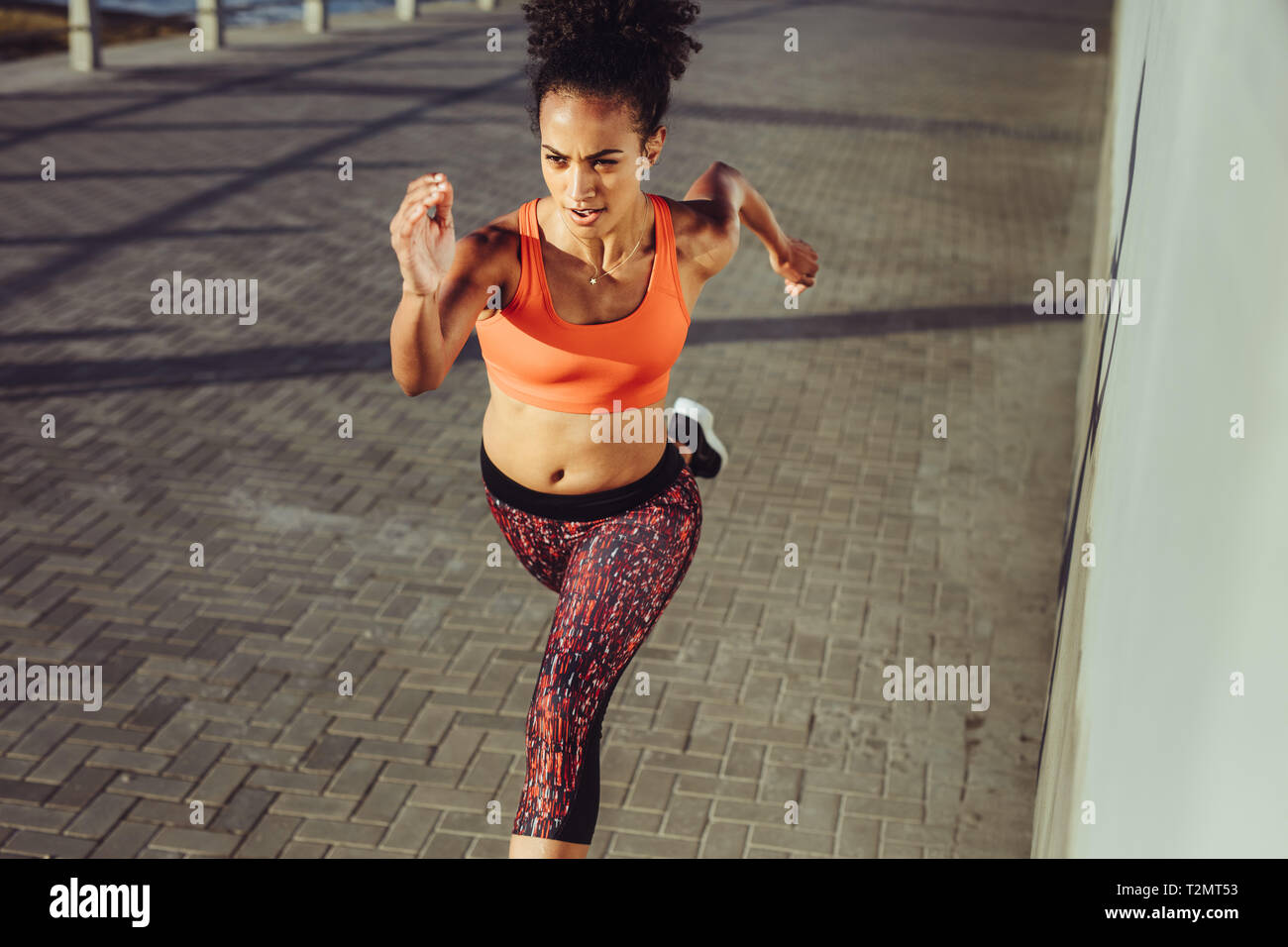 Passen junge Frau sprintet auf dem Bürgersteig. Weibliche in Sportswear schnell an der Promenade laufen. Stockfoto