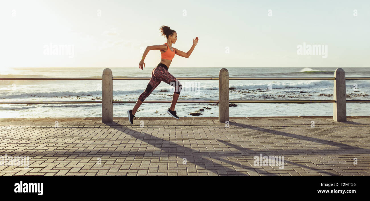 Sportliche junge Frau, die an der Strandpromenade. Seitenansicht des Läuferin sprinten im Freien. Stockfoto