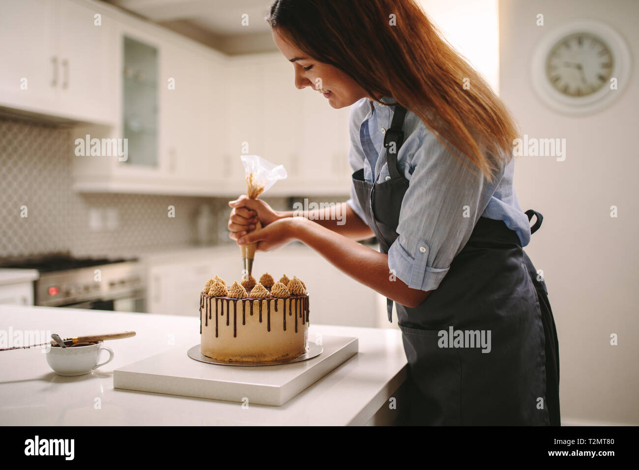 Köchin dekorieren Kuchen mit Schlagsahne mit Party Tasche. Frau im Vorfeld der Vorbereitung einen leckeren Kuchen zu Hause. Stockfoto