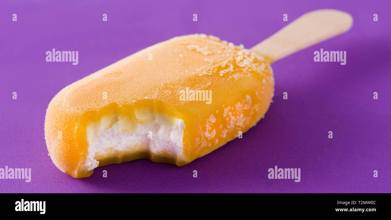 Orange popsicle auf Violett Hintergrund. Panoramaaussicht Stockfoto