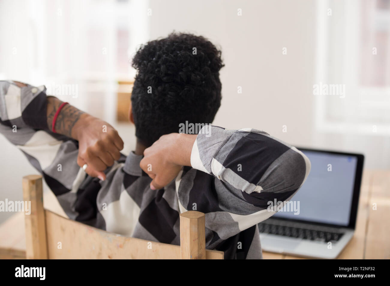 Ansicht der Rückseite schwarz Business Woman oder Schüler Mädchen am Schreibtisch im Büro am Arbeitsplatz die Arbeit beendet, Stretching Arme. Frau fühlt sich gut kein stre Stockfoto