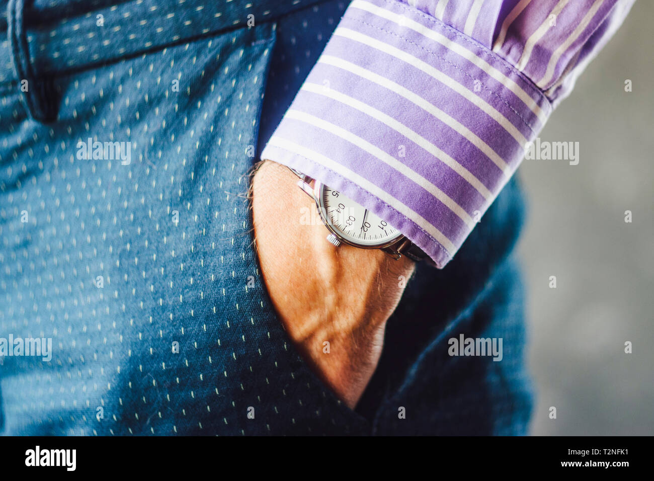 Nahaufnahme der männlichen Hand in der Hosentasche mit eleganten Armbanduhr. Kaukasische Geschäftsmann in gestreiften Hemd tragen stilvolle Kleidung aufpassen. Mode und Punctua Stockfoto