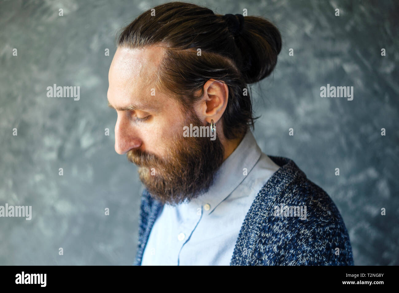 Mode Portrait einer Nachdenklich, bärtiger Mann mit einem blauen Hemd und Blau Strickjacke auf grauem Hintergrund. Rücksichtnahme Konzept Stockfoto