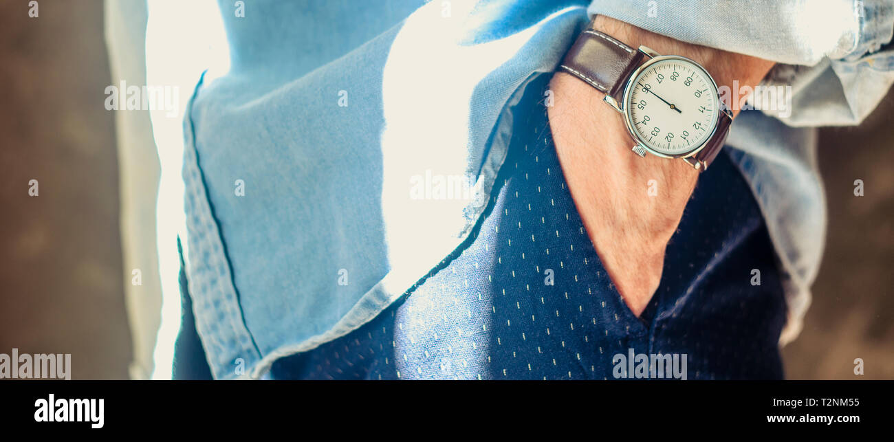 Nahaufnahme der Männer Zubehör elegante Armbanduhren. Die Hand in der Tasche. Shirt Ärmel hochgekrempelt. Informelle Casual Konzept Verschleiß Stockfoto