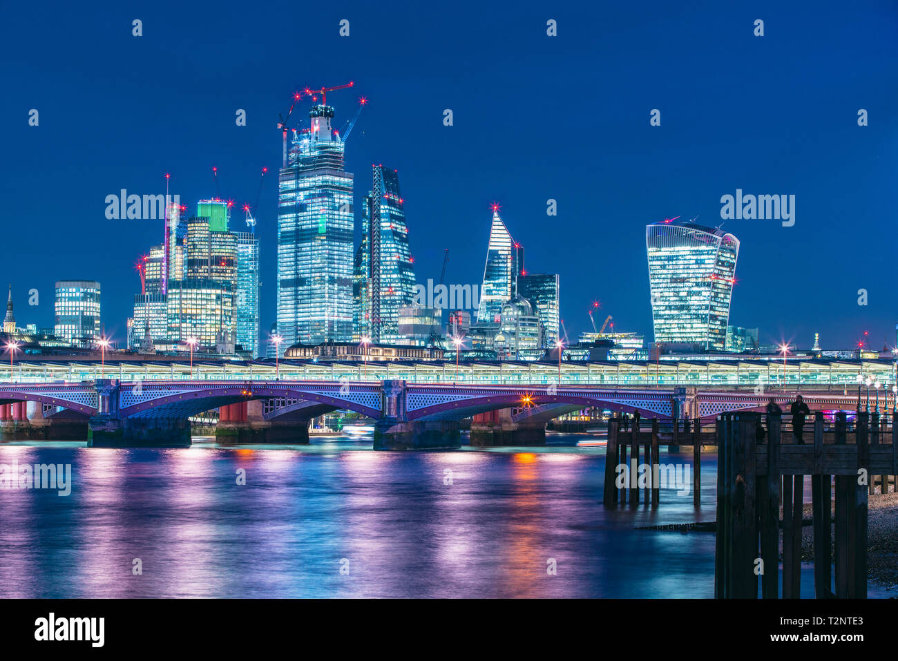 Skyline von Financial District in der Nacht, Thames River im Vordergrund, City of London, Großbritannien Stockfoto