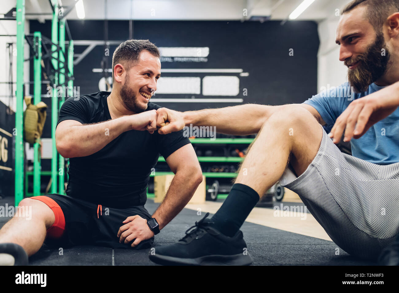 Persönlicher Trainer und Mensch mit Behinderung genießen Gespräch in der Turnhalle Stockfoto