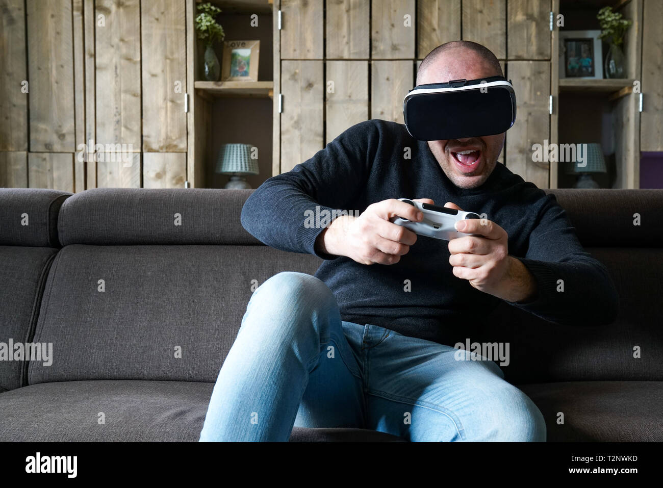 Erwachsenen Mann mit einer Virtual Reality Gaming Headset in sein Wohnzimmer. Erfahrungen mit VR-Headset und Game Controller Stockfoto