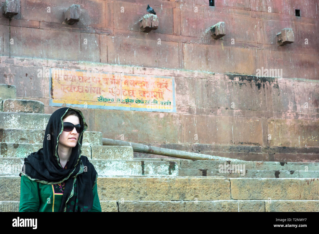 Eine junge Frau, der ein schwarzes Kopftuch, sitzt auf der Ghat in Varanasi. Stockfoto