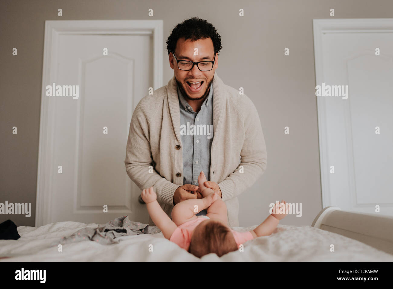 Vater dressing baby Tochter auf dem Bett im Schlafzimmer Stockfoto