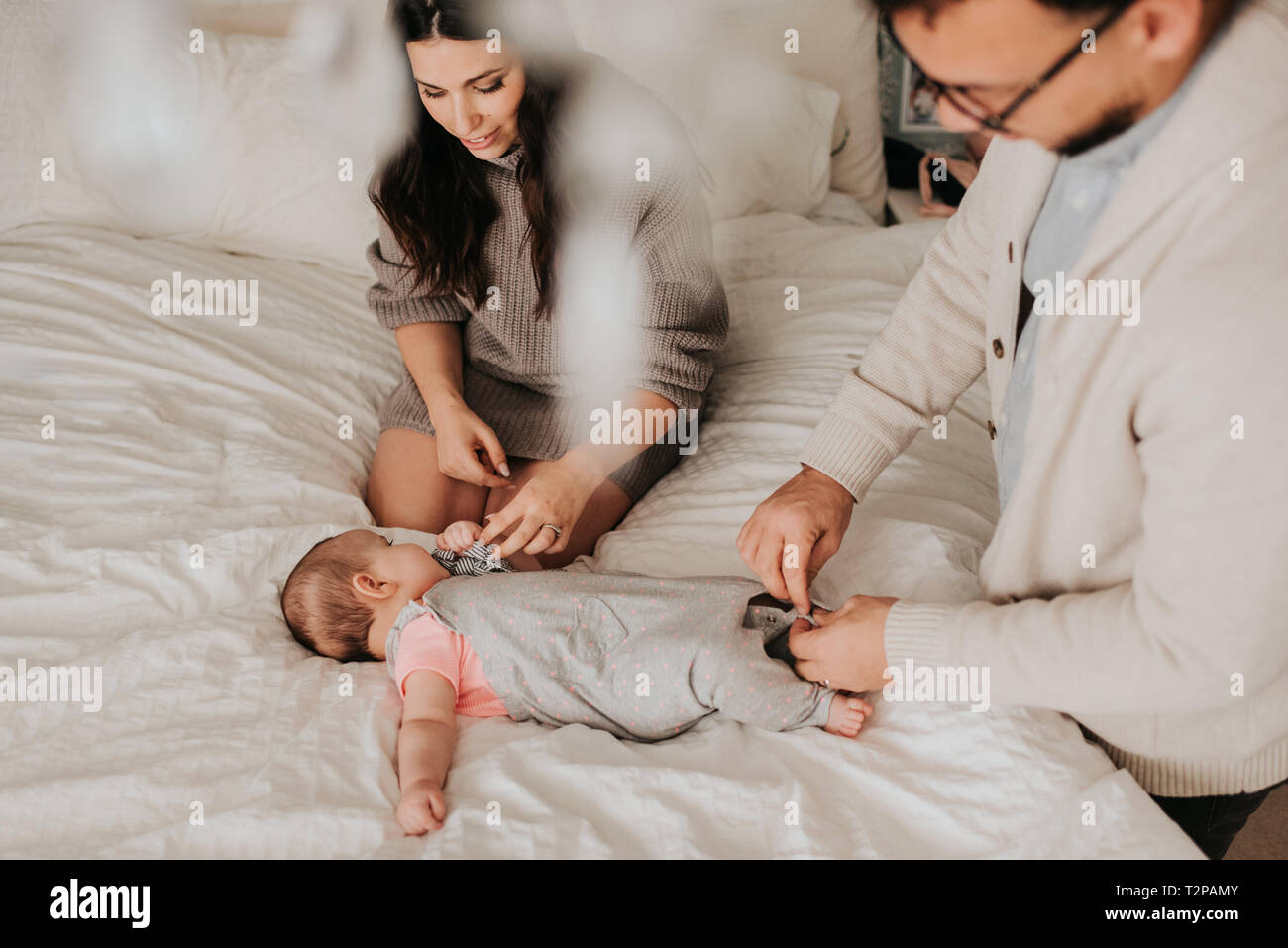 Paar dressing baby Tochter auf dem Bett im Schlafzimmer Stockfoto