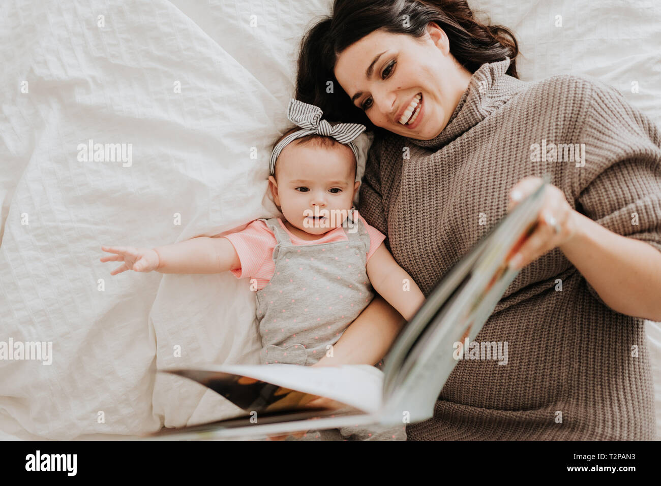 Mutter Lesung mit Baby Tochter auf dem Bett Stockfoto