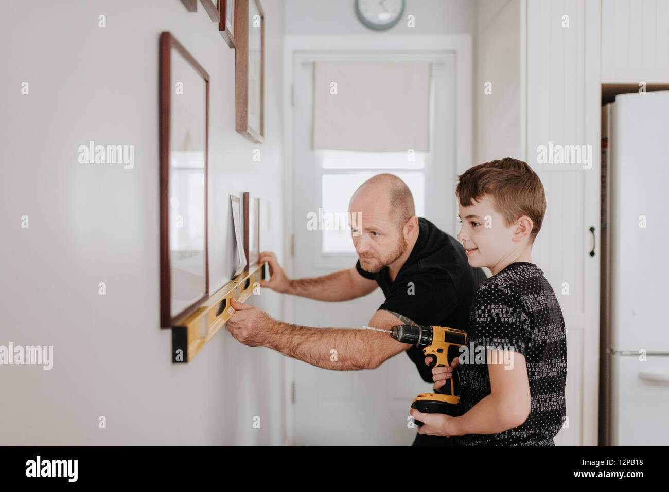 Vater lehre Sohn bohren Wand für Bilderrahmen Stockfoto