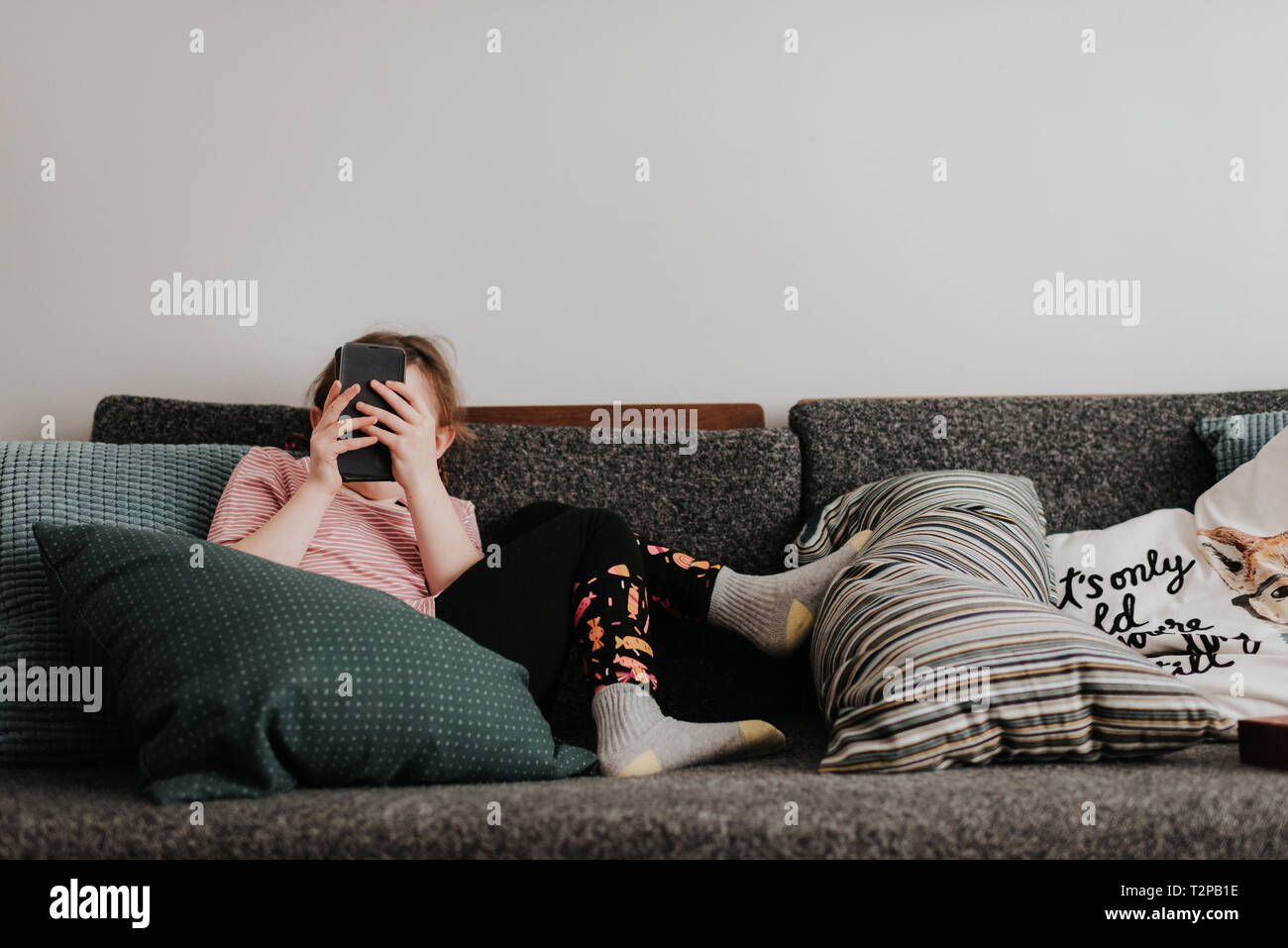 Mädchen spielen mit Smartphone auf der Couch Stockfoto