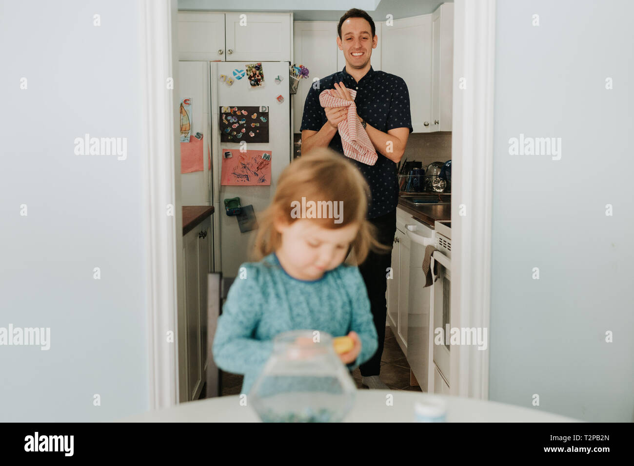 Weibliche Kleinkind an Tisch und Vater in der Küche Stockfoto