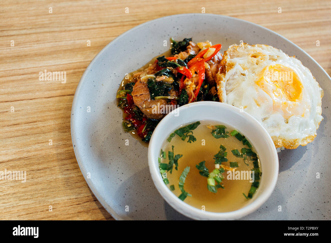 Thai Basil geschmortes Schweinefleisch mit Spiegelei und Reis zusammen mit Suppe am Tisch lagen Stockfoto