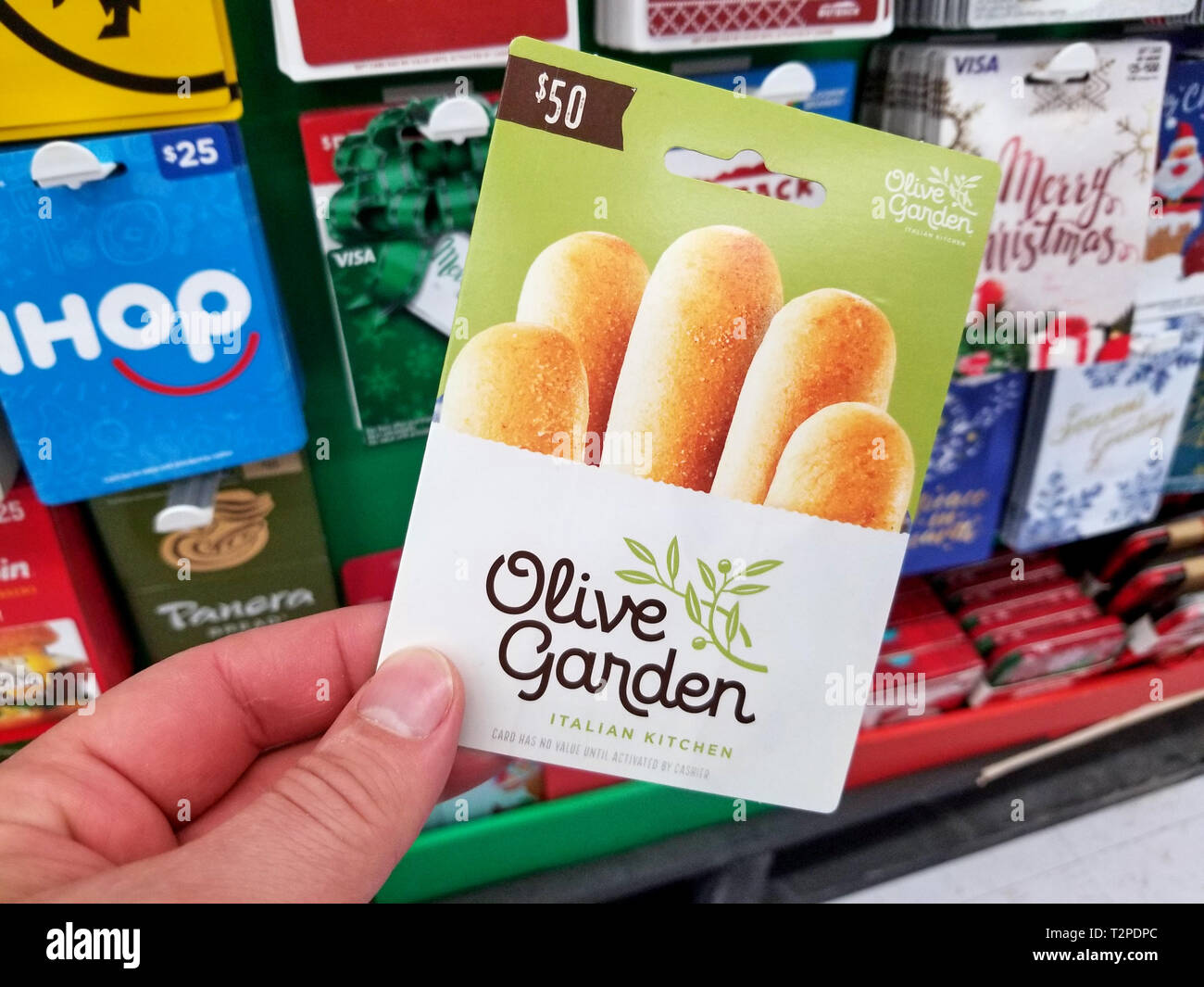 PLATTSBURGH, USA - Januar 21, 2019: Olive Garden italienische Küche Geschenkkarte in eine Hand über ein Regal mit verschiedenen Geschenkgutscheinen in einem Walmart Stores. Stockfoto