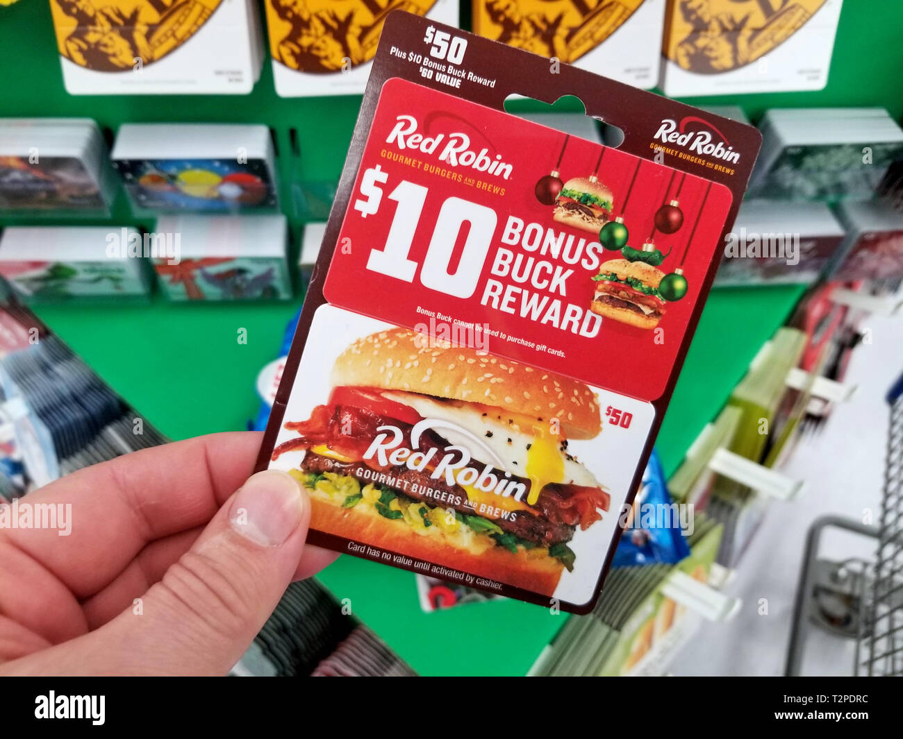 PLATTSBURGH, USA - Januar 21, 2019: Red Robin Geschenkkarte in eine Hand über ein Regal mit verschiedenen Geschenkgutscheinen in einem Walmart Stores. Stockfoto