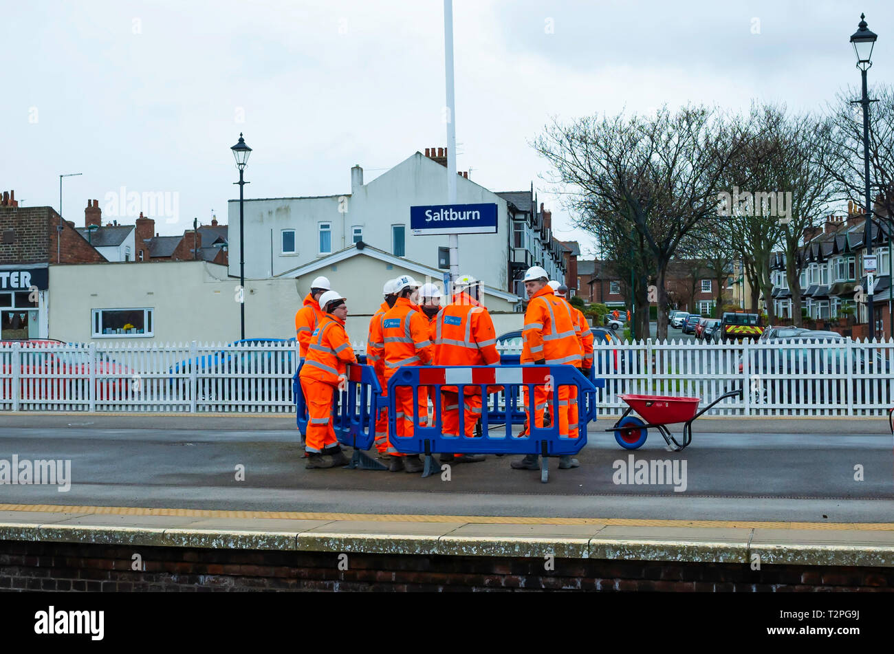 Eine Bande von Eisenbahnunternehmen, die Arbeiter in orange Overalls diskutieren einen Job auf der Plattform in der saltburn North Yorkshire Stockfoto