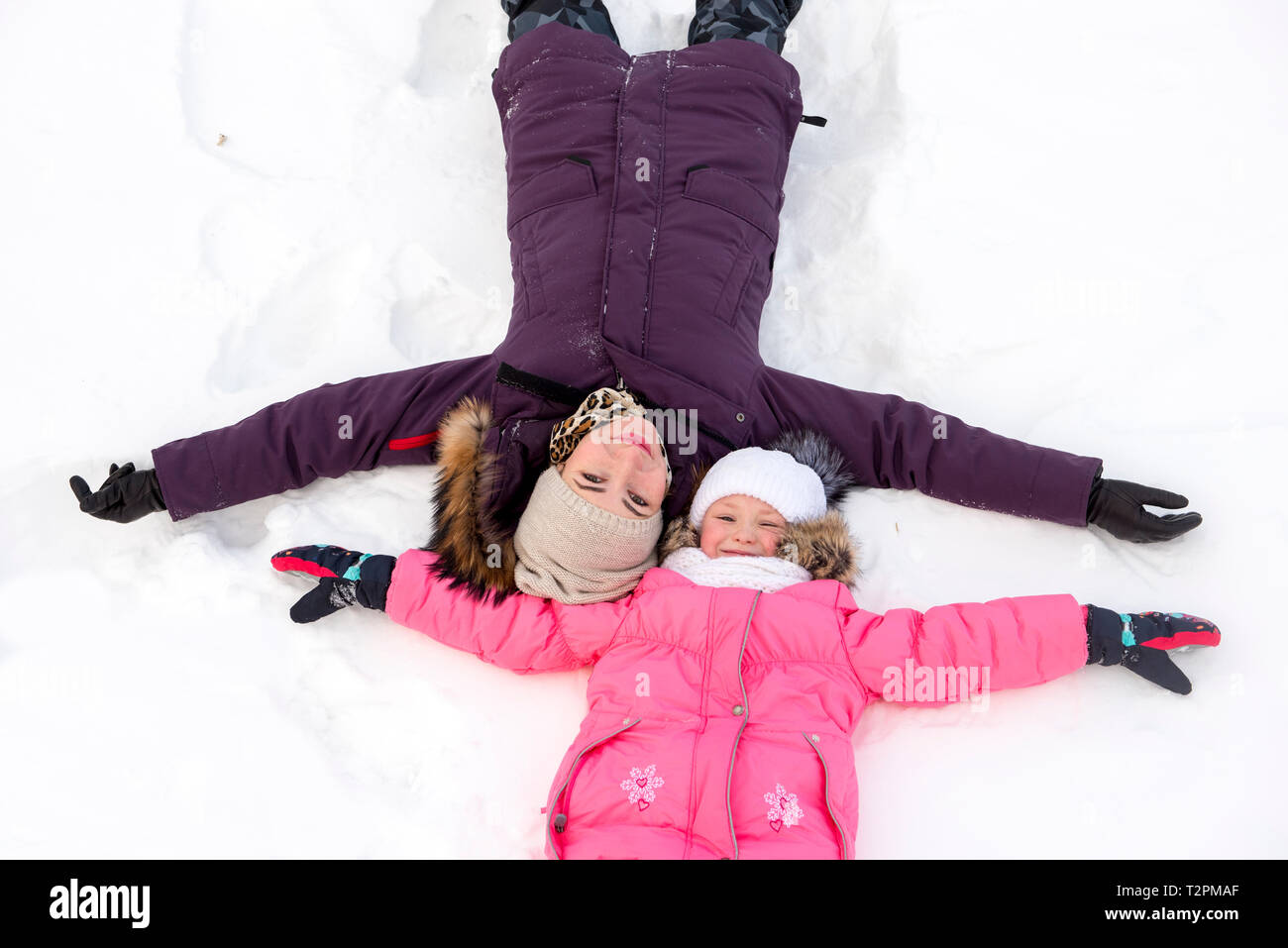 Mutter und Tochter machen Schnee Engel Stockfoto