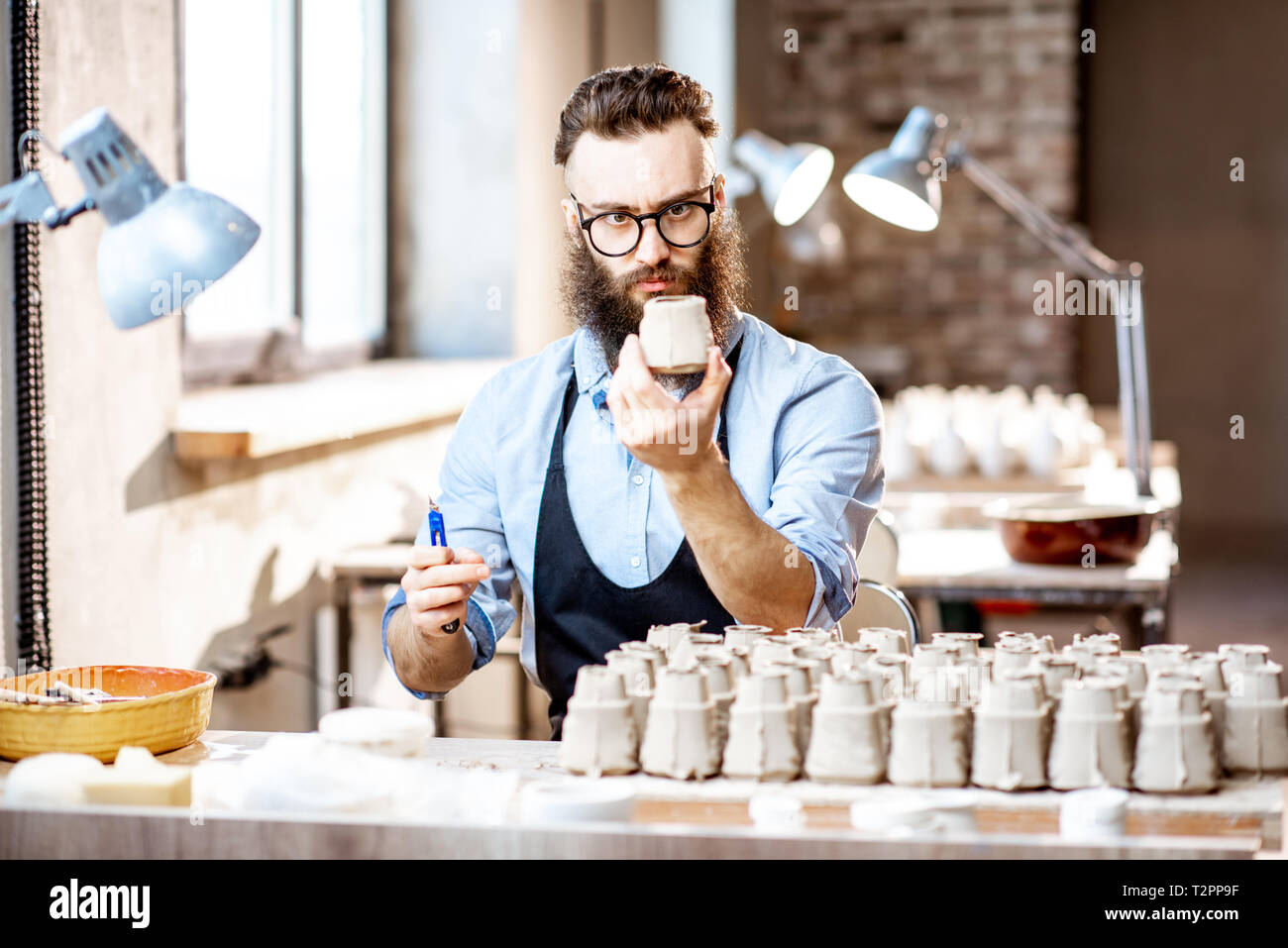 Gut aussehender bärtiger Mann arbeiten mit keramischen Werkstücken am Arbeitsplatz in der Töpferei shop Stockfoto