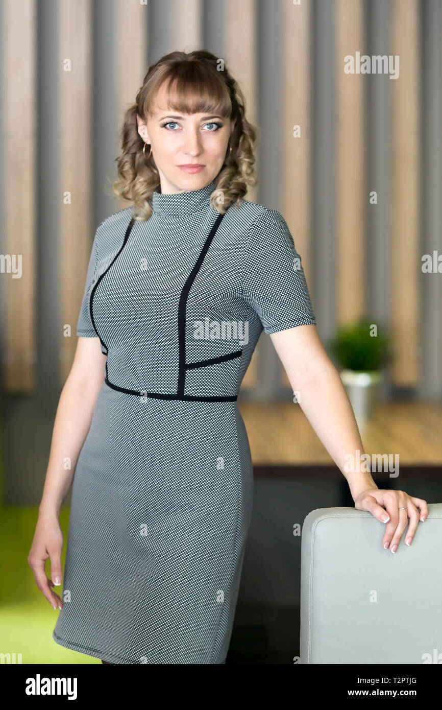 Frau 30-35 Jahre alt in einem grauen Kleid in einem Cafe Stockfoto