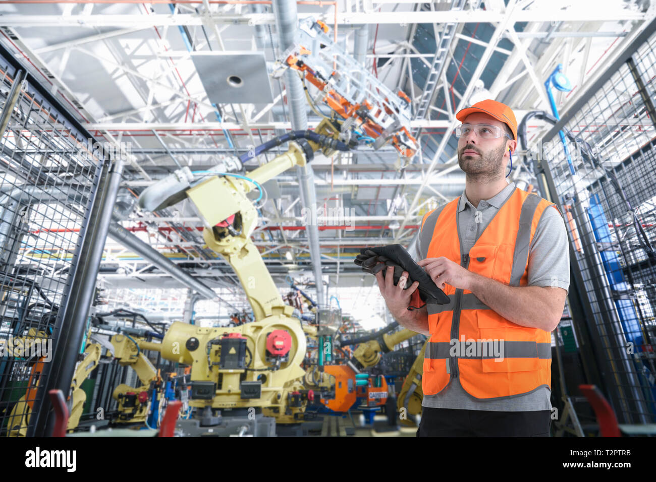 Das zusammengesetzte Bild im Auto mit digitalen Tablet mit Roboter im Auto Fabrikarbeiter Stockfoto