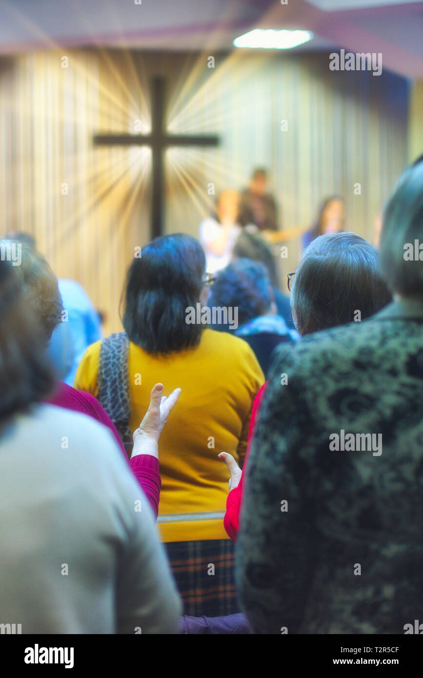 Christliche Gemeinde Gottesdienst gemeinsam Gott, mit Kreuz mit Lichtstrahlen im Hintergrund Stockfoto