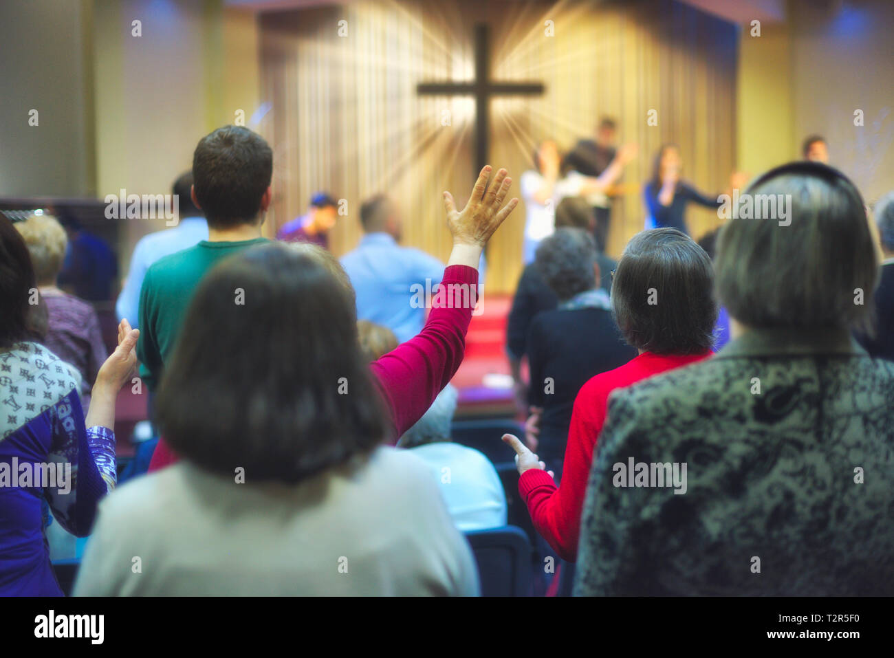 Christliche Gemeinde Gottesdienst gemeinsam Gott, mit Kreuz mit Lichtstrahlen im Hintergrund Stockfoto