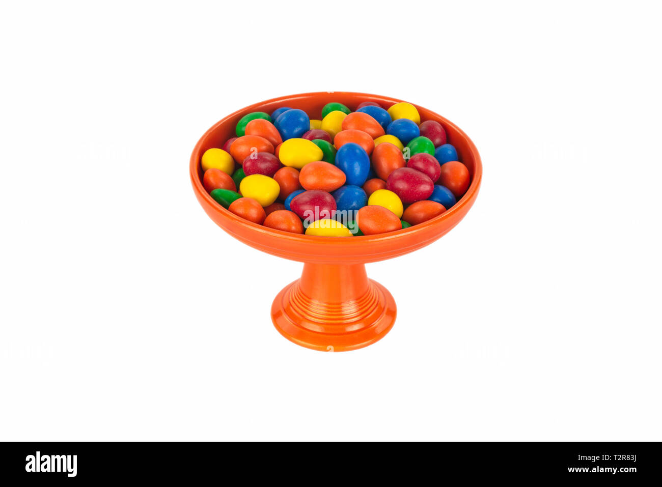 Helles Orange Vintage Fiesta Ware Sockel Candy Servierteller mit einer Auswahl an bunten Süßigkeiten. Anspruchsvolle und isoliert auf Weiss. Stockfoto