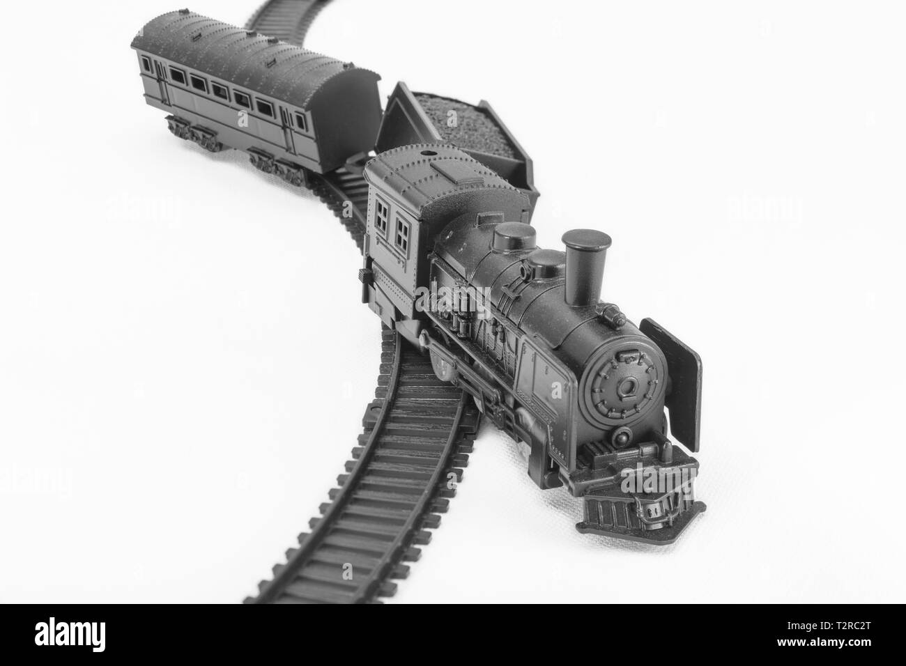 Schwarz lackiertes Spielzeugmodell mit Dampfmaschine. Für abseits der Strecke, finanziellen Crash, vom Kurs abgekommen, Zugunfall, ups, Entgleisung, SVB-Bank-Kollaps-Metapher Stockfoto