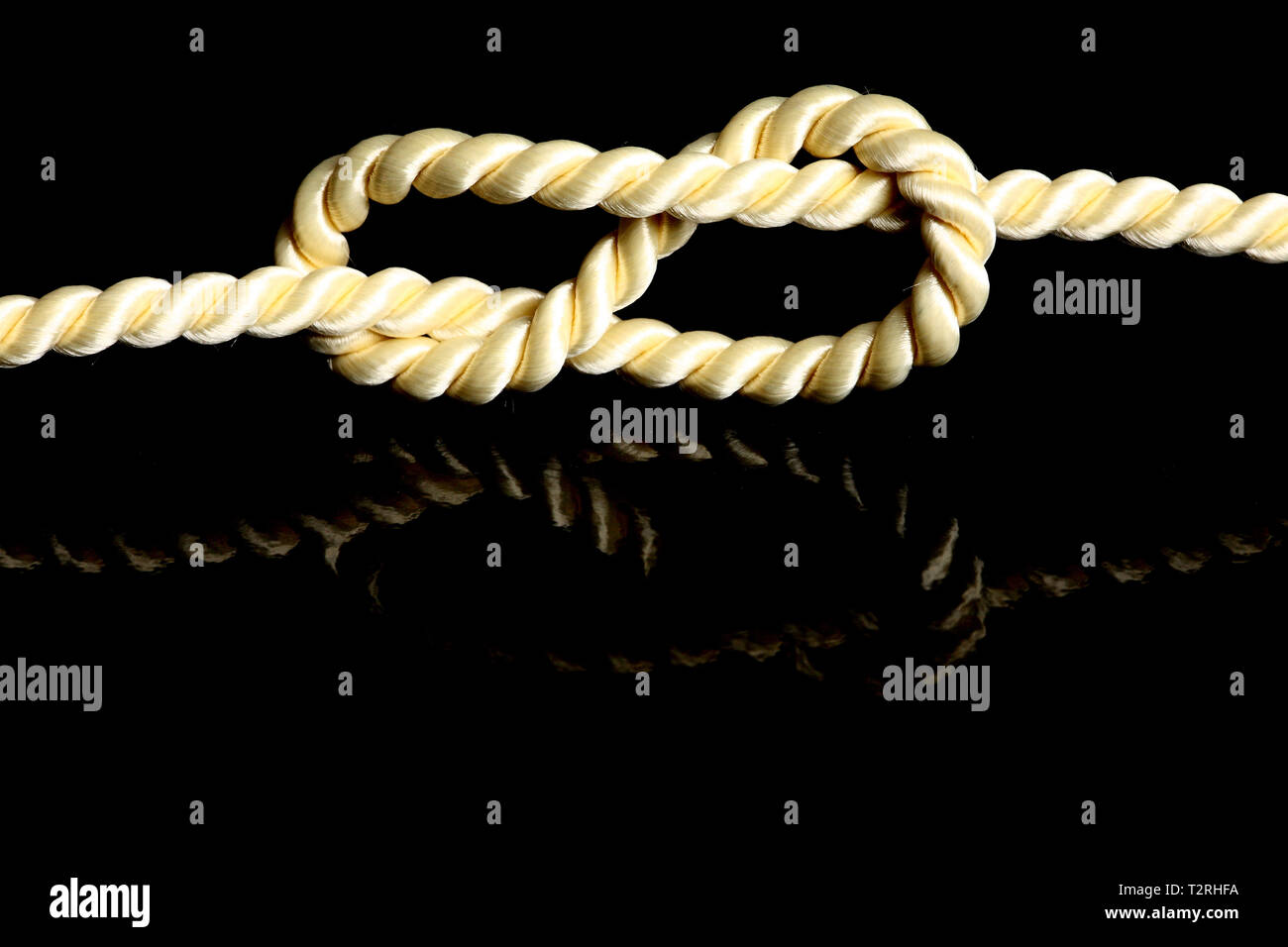 Ein Knoten vor einem schwarzen Hintergrund. Der Knoten wird auf dem Hintergrund reflektiert. Stockfoto