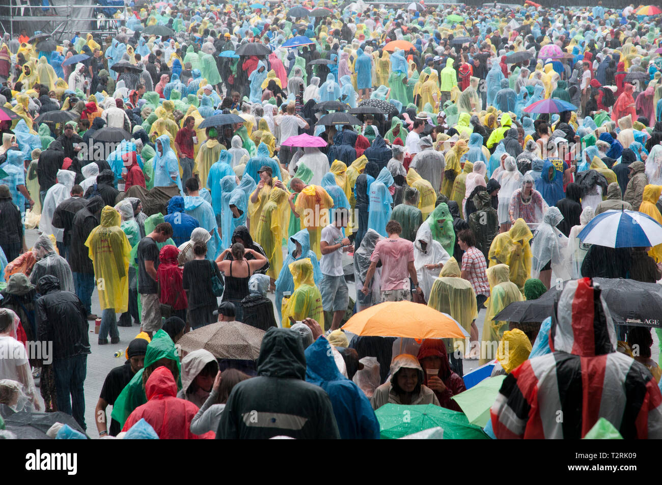 Menschenmassen, die beim Rockkonzert im strömenden Regen stehen Stockfoto