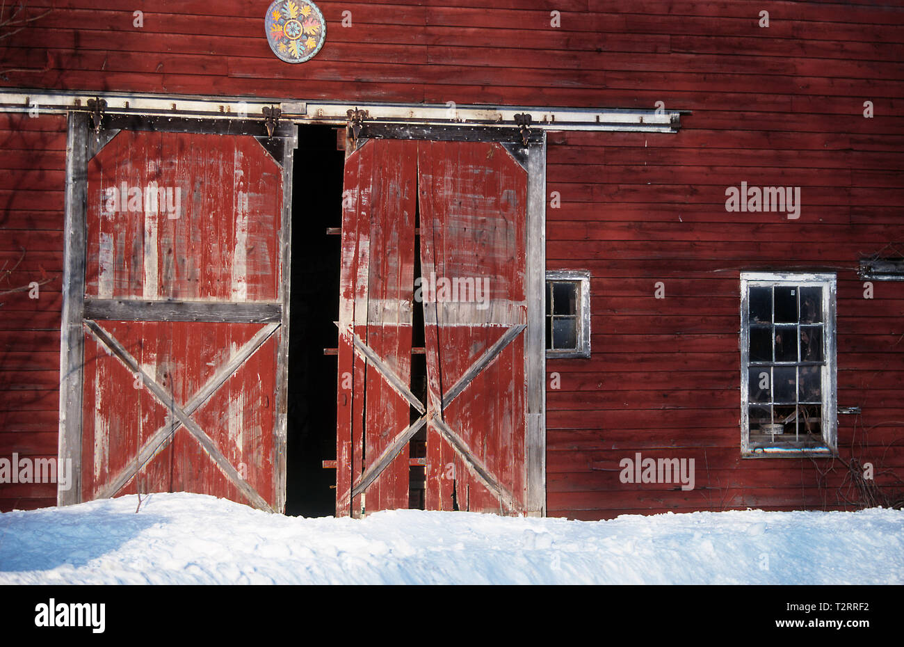 Verblasste rote hölzerne Schiebetür Scheune Türen auf einer Farm in Vermont im Schnee Stockfoto